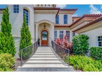 Elegant home entrance with a tiled staircase, lush landscaping, and an arched wooden front door at 362 41St Ave, St Pete Beach, FL 33706