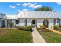 Charming villa featuring a pristine white exterior, a metal roof, and delightful landscaping under a beautiful blue sky at 4227 Glissade Dr, New Port Richey, FL 34652