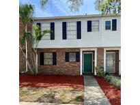 Two-story townhouse with white siding, black shutters, brick accents and a well-manicured lawn at 4624 W North B St, Tampa, FL 33609