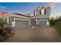 Beautiful home with a three car garage and a brick paved driveway at sunset at 4777 Ballantrae Blvd, Land O Lakes, FL 34638