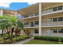 Condo exterior showcasing multi-level balconies, manicured landscaping, and entryways with well-kept lawns and walkways at 870 Virginia St # 109, Dunedin, FL 34698