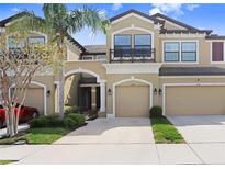 Townhouse exterior with manicured lawn, neutral paint, covered entrance and two-car garage at 11521 Crowned Sparrow Ln, Tampa, FL 33626