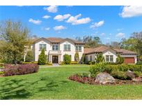 Stately two-story home with a tile roof, manicured lawn, and beautiful landscaping and flower beds at 16119 Carencia Ln, Odessa, FL 33556