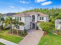 Stunning two-story home featuring a tile roof, a brick paver driveway and lush landscaping at 30900 Spruceberry Ct, Wesley Chapel, FL 33543