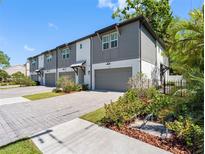 Newly constructed townhomes featuring gray and white exterior, private garages, and paver driveways at 410 S Church Ave, Tampa, FL 33609