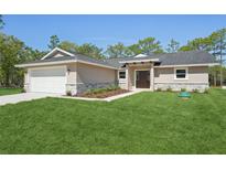 Charming single-story home featuring a well-manicured lawn, stone accents, and a two-car garage at 15409 Coot Rd, Weeki Wachee, FL 34614
