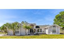 Charming single-story home features a well-manicured lawn, mature trees, and elegant architectural details at 2449 Running Oak Ct, Spring Hill, FL 34608