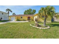 Charming yellow home featuring a well-maintained lawn and mature palm trees, creating inviting curb appeal at 8408 Flagstone Dr, Tampa, FL 33615