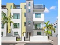 Modern townhome boasts a colorful facade, multiple balconies, and a landscaped front yard at 907 Arlington N Ave, St Petersburg, FL 33705