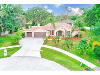 Beautiful single-story home with a three-car garage, well-manicured lawn, and mature landscaping at 12302 Knight Pl, Thonotosassa, FL 33592
