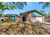 Charming single-story home featuring brick accents, a two-car garage, and an American flag at 3051 Egret Ter, Safety Harbor, FL 34695