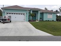 Charming single-story home with a well-manicured lawn, teal exterior, and a spacious driveway at 3190 Darius Ave, North Port, FL 34288