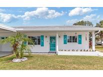 Charming single-story home featuring a well-manicured lawn, bright turquoise shutters, and a welcoming entryway at 6801 Clark St, Hudson, FL 34667