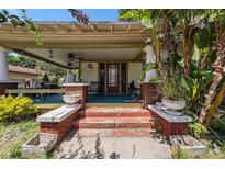 Inviting front porch with brick accents and a covered seating area, framed by mature trees and colorful plantings at 910 E North Bay St, Tampa, FL 33603