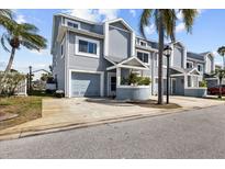 Charming townhouse with light-blue siding, well-manicured landscaping, and a private garage at 911 Harbour House Dr, Indian Rocks Beach, FL 33785