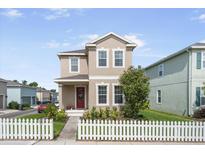 Charming two-story home featuring a red door, white picket fence, and manicured landscaping at 11109 Great Neck Rd, Riverview, FL 33578