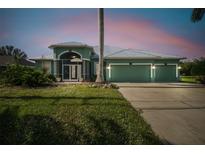 Charming single-story home with a spacious three-car garage, lush lawn, and inviting screened entryway at 1161 Rio De Janeiro Ave, Punta Gorda, FL 33983