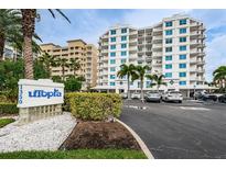 Beautiful Utopia condo building with lush landscaping and a well-maintained parking area at 1350 Gulf Blvd # 502, Clearwater Beach, FL 33767