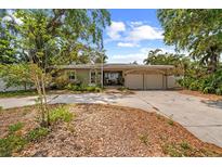 Charming single-story home with mature trees and a spacious driveway leading to a two-car garage at 219 Rialto Ne Way, St Petersburg, FL 33704