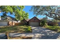 Charming single Gathering brick home featuring a manicured front yard and attached garage in a quiet neighborhood at 3527 Greenglen Cir, Palm Harbor, FL 34684