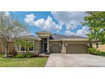 Beautiful single-story home with a well-manicured lawn, mature landscaping, and a two-car garage at 4839 Pointe O Woods Dr, Wesley Chapel, FL 33543