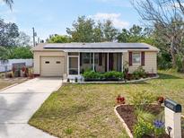 Charming home featuring solar panels, a screened porch, lovely landscaping, and a freshly mulched flower bed at 5050 68Th N Way, St Petersburg, FL 33709