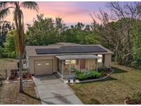 Charming single-Gathering home featuring solar panels, a screened-in porch, and a well-manicured front yard at dusk at 5050 68Th N Way, St Petersburg, FL 33709