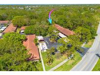 An aerial view of Scottsdale Villas I shows lush landscaping, mature trees and tile roofs at 1201 Montrose Pl, Dunedin, FL 34698