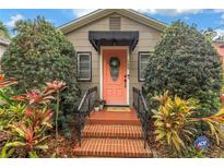 Charming home entrance with a vibrant coral door, black awning, and beautifully landscaped surroundings at 138 17Th N Ave, St Petersburg, FL 33704