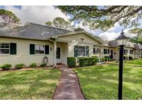 Charming single-story home featuring a well-manicured lawn and lovely landscaping with decorative shutters and walkway at 1466 Normandy Park Dr # 4, Clearwater, FL 33756