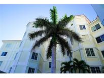 Exterior angle shot of cream and white condominium building with a red tile roof and a palm tree in front of it at 1860 N Fort Harrison Ave # 301, Clearwater, FL 33755