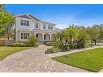 Stunning two-story home with well-manicured lawn and brick driveway, complemented by lush tropical landscaping at 47 Martinique Ave, Tampa, FL 33606
