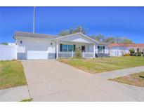 Charming single-story home featuring a well-maintained lawn, a white picket fence, and an attached garage at 7827 Crosier Ct, New Port Richey, FL 34653