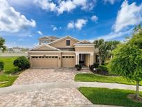 Inviting two-story home featuring a three-car garage, brick driveway, and a beautifully landscaped front yard at 8578 Gibbons Grove Loop, Land O Lakes, FL 34637