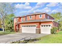 Beautiful two-story home featuring an attached two-car garage, an orange facade, and well-maintained landscaping at 9102 Kentucky Day Ct, Gibsonton, FL 33534