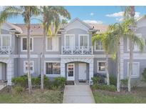 Charming townhome exterior featuring a well-manicured lawn and mature palm trees, offering a welcoming curb appeal at 18187 Paradise Point Dr, Tampa, FL 33647