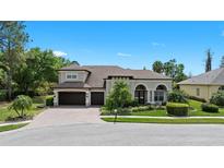 Charming home with lush landscaping, brick driveway, and three-car garage on a serene day at 21654 Draycott Way, Land O Lakes, FL 34637