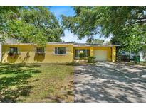 Charming yellow single-story home with well-manicured lawn and mature trees. Includes a one car garage at 3409 W El Prado Blvd, Tampa, FL 33629