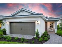 Charming home featuring a two-car garage, well-manicured landscaping, and a cozy front porch at 6132 Wire Grass Ct, Nokomis, FL 34275