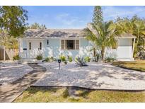 Charming single-story home with a light blue exterior, complemented by modern landscaping with white gravel and a walkway at 747 39Th Ne Ave, St Petersburg, FL 33703