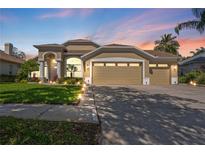 Charming home with a three-car garage and manicured lawn, beautifully lit at dusk at 9905 Woodbay Dr, Tampa, FL 33626