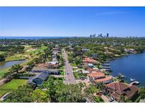 Stunning aerial view of a coastal home near a golf course and waterfront with city skyline in the distance at 1344 Monterey Ne Blvd, St Petersburg, FL 33704