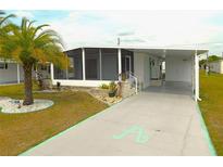 Charming home featuring a large, screened lanai, carport, and beautiful palm tree in the front yard at 5244 Betty St, Zephyrhills, FL 33542