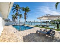 Waterfront home with a private pool, sun loungers, and dock on a sunny day at 728 Pruitt Dr, Madeira Beach, FL 33708