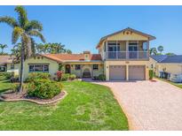 Charming two-story home featuring a two-car garage, brick driveway and lush landscaping with mature palm tree at 1140 81St S St, St Petersburg, FL 33707