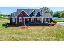 Charming red two-story home with a covered porch and beautifully landscaped front yard at 14807 Capps Estates Ln, Wimauma, FL 33598