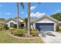 Charming single-story home featuring a well-maintained lawn and a two-car garage with a blue door at 8847 Bel Meadow Way, Trinity, FL 34655