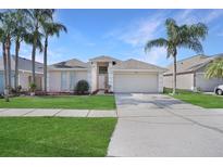 Charming single-story home with a two-car garage, well-manicured lawn, and tropical palm trees enhancing its curb appeal at 10275 Oasis Palm Dr, Tampa, FL 33615
