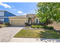 Charming single-Gathering home featuring a manicured lawn, paver driveway, and attached two-car garage at 11327 Emerald Shore Dr, Riverview, FL 33579