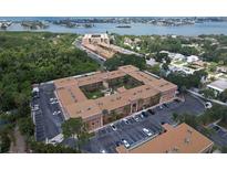 A beautiful aerial view of a condo complex with brick facade, mature landscaping, and ample parking near waterfront at 12760 Indian Rocks Rd # 579, Largo, FL 33774